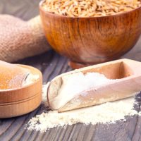 The  flour pile and wheat grains in wooden spoon and bowl on wooden